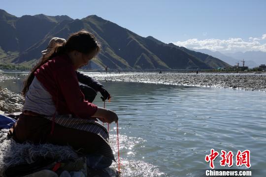 60岁的藏族老人巴金在河水中清洗法器。　孙翔 摄